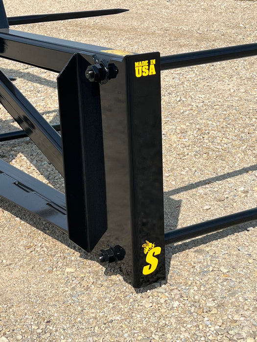 Heavy-duty bale spear from Stinger Attachments moving hay bales across open field – ideal for large-scale agricultural use.