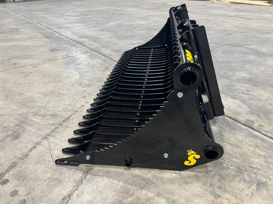 Operator using compact rock bucket to separate rocks from soil – strong, efficient attachment for landscaping and construction work.