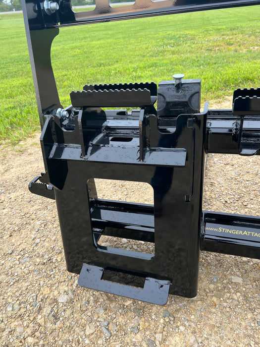 Operator using Stinger skid steer pallet forks to lift stacked pallets – professional-grade attachment built for construction and warehouse work.