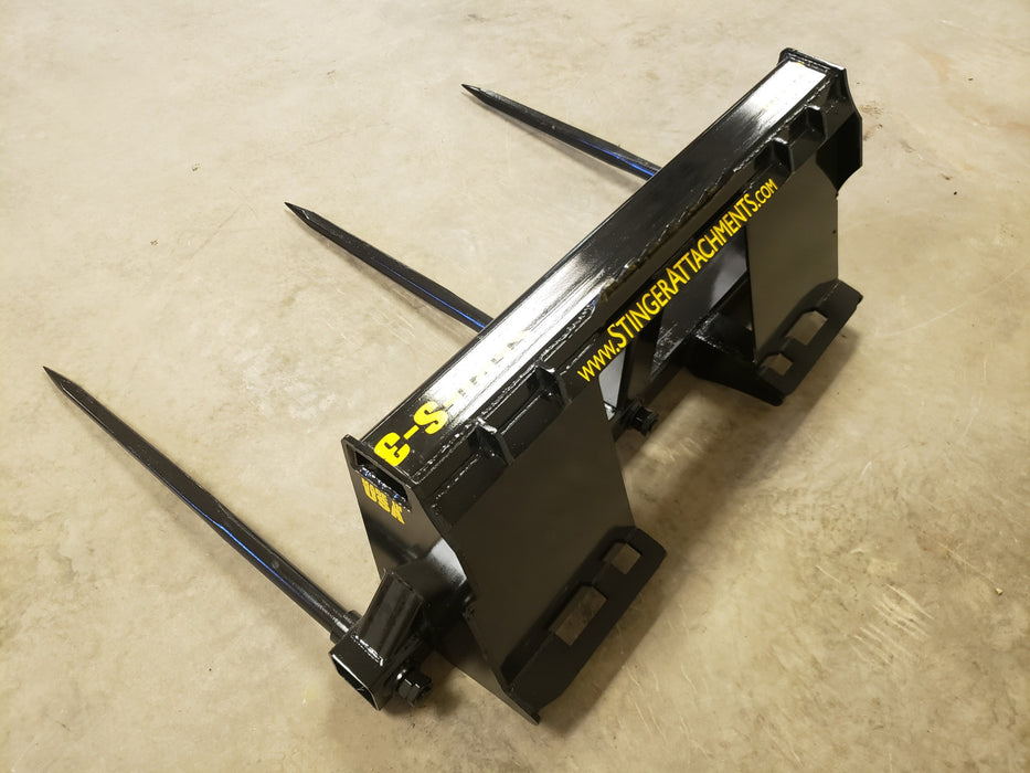 Farmer using Stinger Series 3 bale spear to move hay bales across pasture – professional-grade attachment built for daily farm tasks.