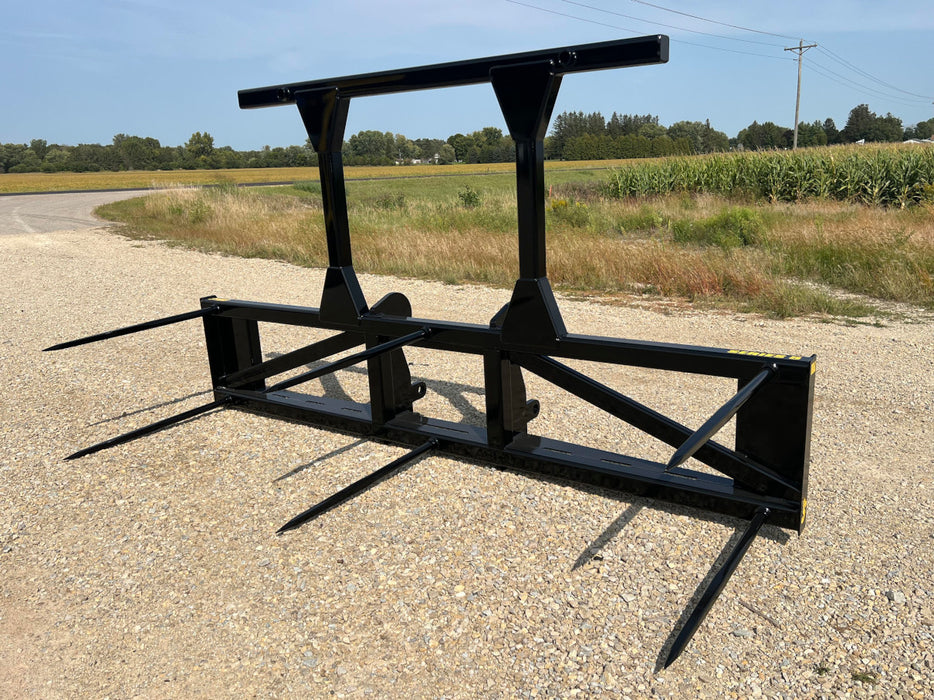 Durable skid steer bale spear by Stinger lifting multiple bales in pasture – heavy-duty multi-bale mover designed for strength and reliability.