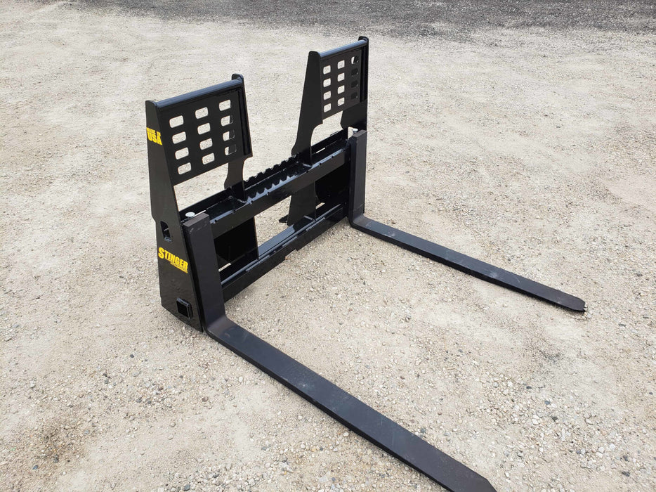 Operator maneuvering skid steer pallet forks to load truck – efficient and rugged design for smooth lifting operations.
