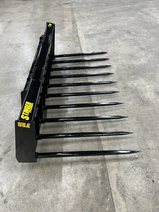 Heavy-duty skid steer grapple bucket by Stinger with manure spears gripping hay bales – durable and versatile attachment for agricultural use.
