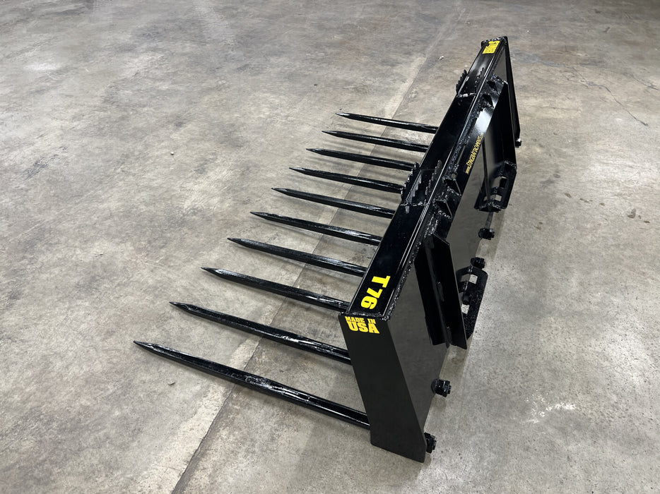 Stinger skid steer grapple bucket lifting hay bale in feedlot – heavy-duty attachment designed for maximum productivity and durability.