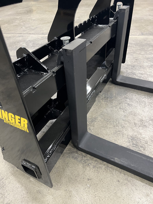 Front view of Stinger skid steer pallet forks under wooden pallet – professional-grade tool for lifting, moving, and stacking.