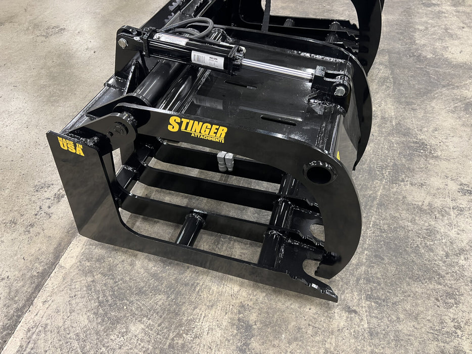 Heavy-duty tractor root grapple attachment gripping large roots with strong hydraulic pressure.