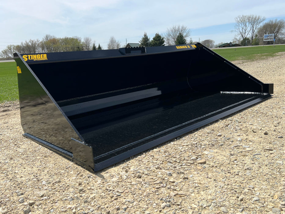 Rugged Stinger skid steer material bucket clearing jobsite debris – essential tool for efficient loading and ground preparation.