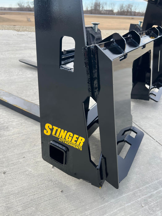 Durable Stinger skid steer pallet forks transporting large load across jobsite – robust Class 2 design provides superior lifting capability.