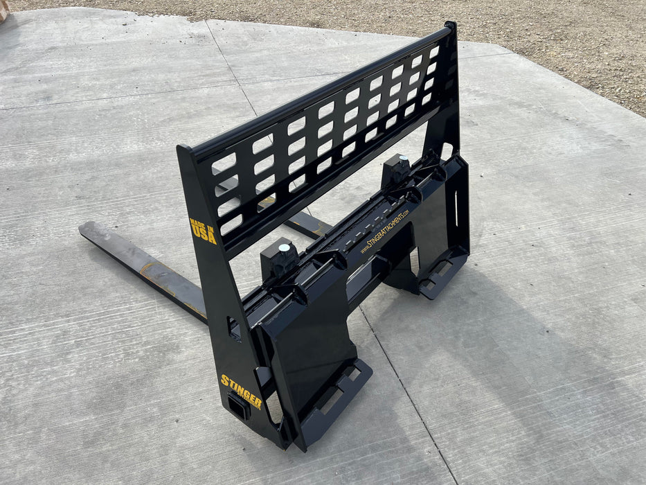 Heavy-duty Stinger skid steer pallet forks attached to loader – ideal for lifting pallets, lumber, and heavy equipment safely.