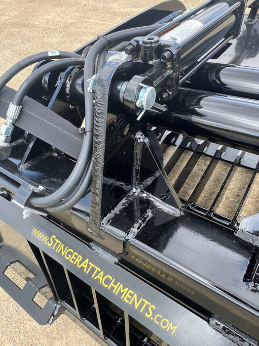 Stinger 48-inch skid steer grapple bucket lifting logs and rubble – efficient attachment for forestry, demolition, and cleanup tasks.