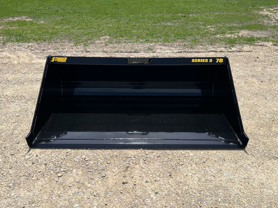 Heavy-duty skid steer material bucket by Stinger scooping soil – durable Series 3 model engineered for maximum strength and capacity.