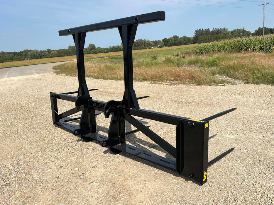 Heavy-duty Bale Spear Series 5XD mounted on a tractor lifting a large round hay bale in an open field.