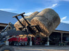 Tractor equipped with a Bale Spear moving multiple round hay bales across a barnyard.