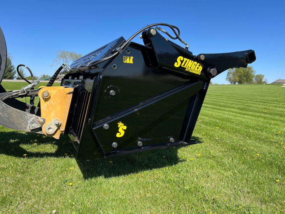 Utility tractor equipped with a tractor rock bucket collecting rocks and soil efficiently on a farm field.