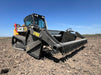 Tractor rock bucket in action, scooping stones and separating fine soil for land preparation.