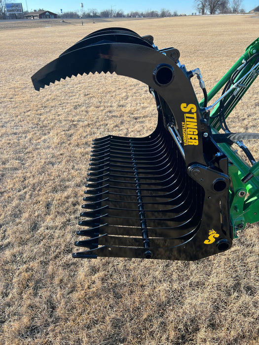 Heavy-duty skid steer grapple bucket with rock tines gripping stones – durable construction built for strength, control, and precision.