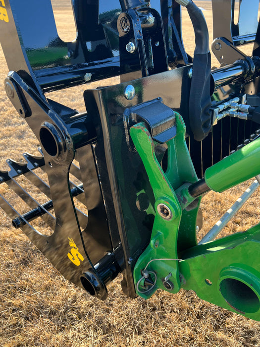 Compact rock skid steer grapple bucket in action clearing field debris – powerful, versatile tool built for maximum efficiency and toughness.