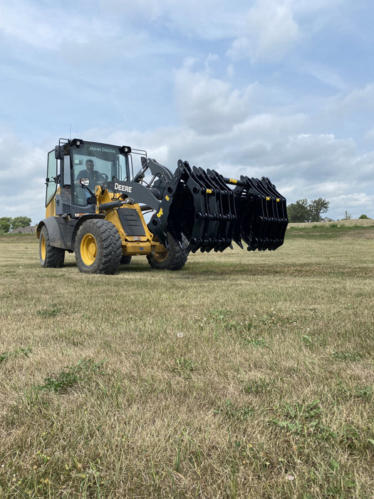 Operator using the CG-XD tractor grapple bucket for heavy land clearing and material transport.