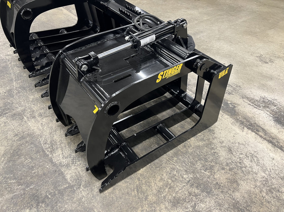 Side view of the Stinger tractor root grapple demonstrating wide jaw opening and hydraulic dual-arm function.