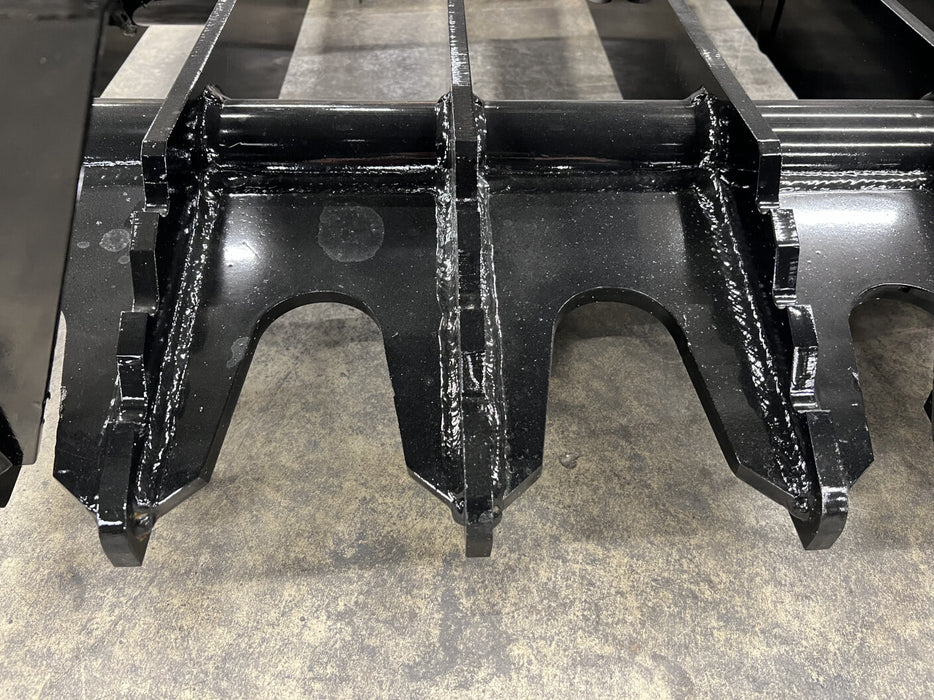 Industrial-grade tractor root grapple resting on gravel ground, highlighting robust frame and weld quality.