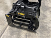 Heavy-duty tractor root grapple attachment gripping large roots with strong hydraulic pressure.